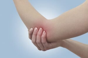 Mujer sujetándose el codo por dolor